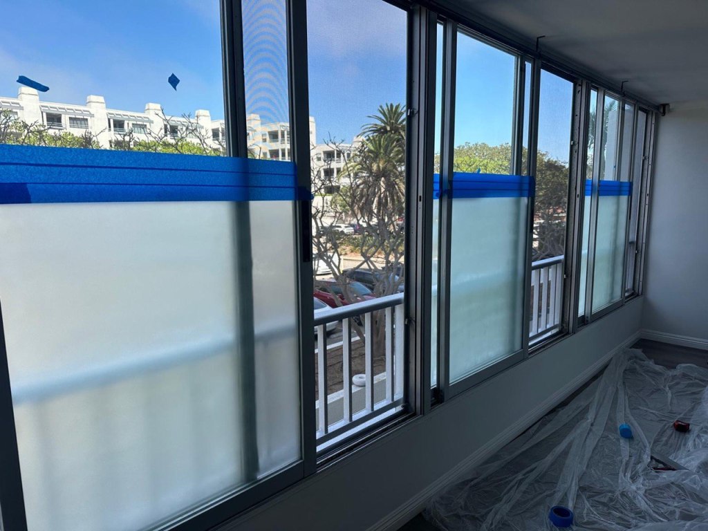Installing frosted window film on apartment windows during work process in Venice