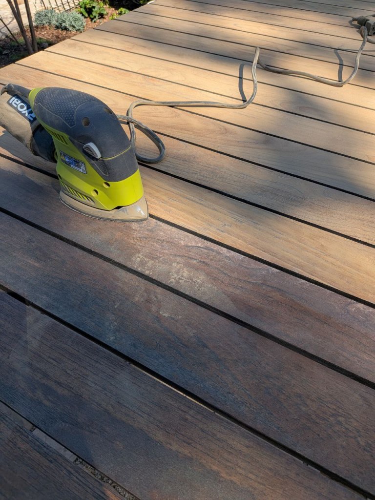Sanding an outdoor wooden patio table during restoration in Toluca Lake